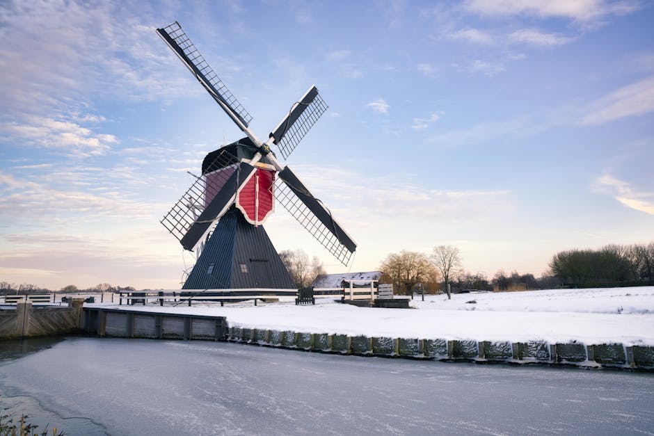 Traditional Dutch windmill in a snowy landscape during winter, showcasing serene beauty.